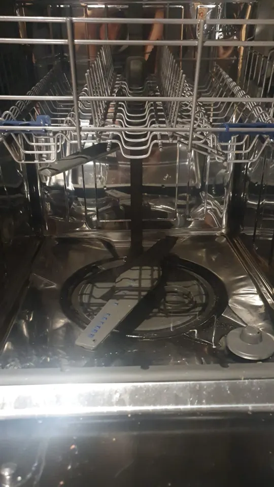 Inside a dishwasher tub with the racks and spray arm