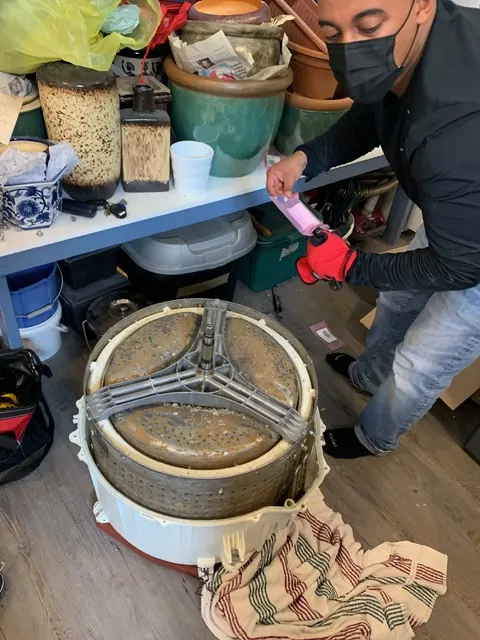 Technician working on the drum and spider arm of a front-load washer